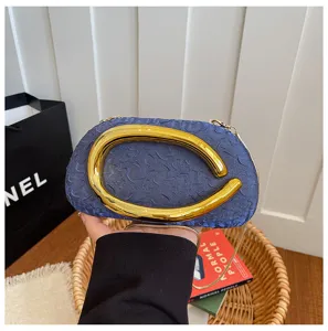 Detailed view of the luxury blue textured evening clutch featuring an oversized gold handle.