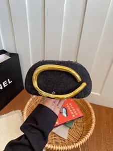 Stylish black evening bag with striking gold abstract metal handle, chic crossbody chain design.