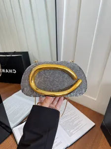 Luxury textured evening clutch bag with prominent gold handle, stylish crossbody design.