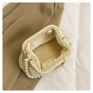 Detailed view of straw woven crossbody bag with elegant pearl handle for summer resort.