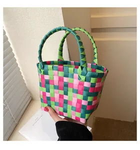 Close-up detail shot of colorful handmade woven handbag featuring vibrant pink and green ribbons.