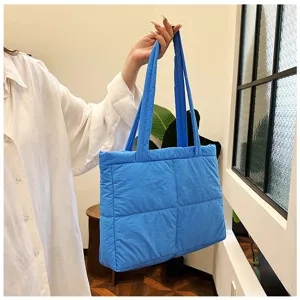 Detail view of blue quilted puffer tote bag, casual shoulder bag for women commute.