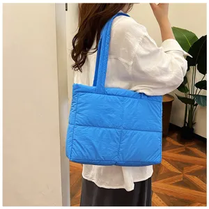 Detailed view of stylish blue quilted puffer shoulder bag, soft casual daily tote for women.
