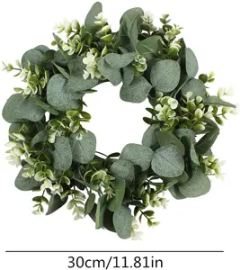 Artificial eucalyptus wreath detail showing green leaves and small white flowers closeup.