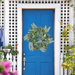 Detailed view of the artificial eucalyptus wreath hanging on a blue door, forest wall decor scene.