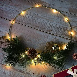 Weihnachten Metallkranz Detail mit warmen LED Lichterketten, Zapfen und dekorativen Beeren.
