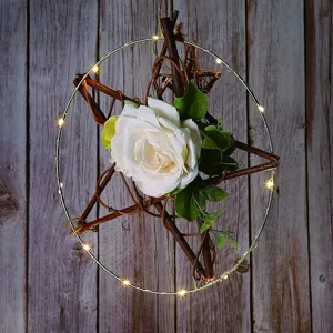 Nahaufnahme des DIY-Metallrings mit Zweigstern, LED-Lichterkette und weißer Rosendekoration.
