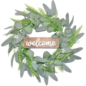 Detailed view of artificial eucalyptus wreath with wooden welcome sign for wall decor.