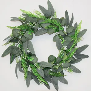Artificial eucalyptus fern wreath detail shot, showing lush green leaves and white flowers clearly.