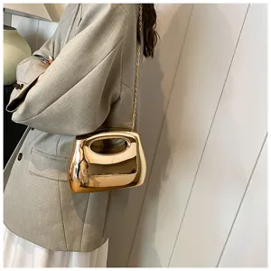 Shiny gold metallic hard shell clutch bag detail, elegant crossbody evening bag for women.