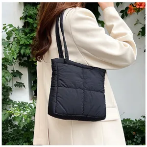 Close-up detail of black quilted puffer shoulder bag, minimalist chic winter style.