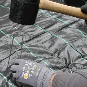 Detaillierte Nahaufnahme der Installation eines U-förmigen Gartenherings in Unkrautvlies.
