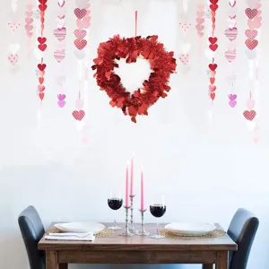 Red tinsel heart wreath hanging decoration with paper heart garlands for Valentine's Day party.