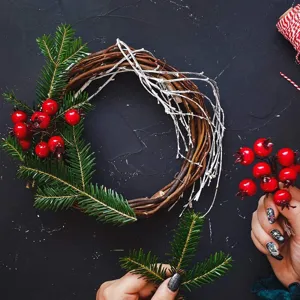 DIY Weihnachts-Zweijkranz mit Tannenzweigen und roten Beeren für festliche Dekoration.