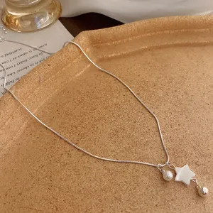 Close-up of elegant silver snake chain necklace with pearl and star pendant, vintage style.