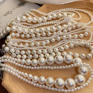 Detailed shot of multi-layer pearl necklaces with mixed sizes and metal beads on a vintage tray.