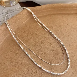 Exquisite double-layer silver necklace detail, featuring a textured bead chain and fine chain.