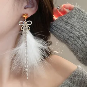 Gros plan détaillé de la boucle d'oreille nœud strass plume avec cristaux scintillants.