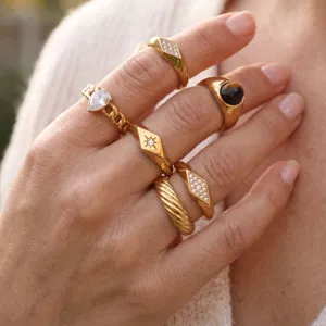 Primer plano detallado de anillos dorados en tendencia apilados con diamantes y piedras.