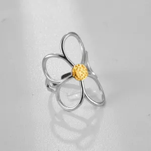 Anillo de flor bicolor en acero inoxidable con pétalos calados y centro dorado texturizado.