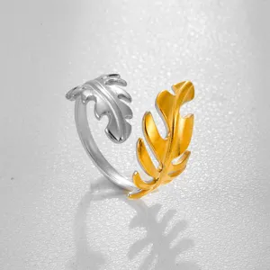Primer plano de detalle de un anillo de acero inoxidable con hojas bicolor plata y oro.