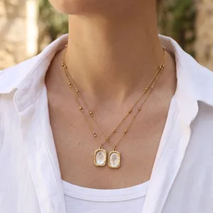 Gold layered necklace with rectangular floral pendant, vintage style jewelry for women.