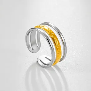 Primer plano detallado del anillo abierto multicapa con diseño texturizado en oro y plata.