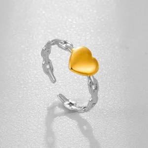 Vista detallada de un anillo de acero inoxidable bicolor con corazón dorado y cadena.