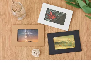 Detailansicht leerer horizontaler Postkartenhüllen und Papierschachteln auf Holztisch.