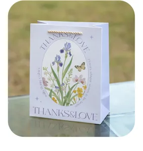 Detailansicht der edlen Papiertragetasche mit frischem Blumenmuster und eleganter Schrift.