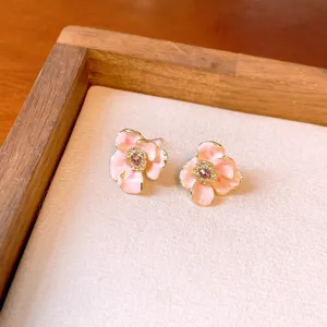 Sweet pink floral enamel stud earrings with sparkling central crystal, elegant gold-trimmed design.