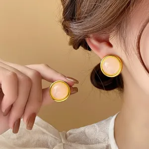 Close-up detail of stylish pink round stone stud earrings with elegant gold rim design.