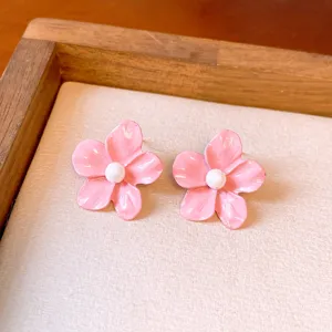 Close-up detail of sweet pink enamel flower stud earrings with white pearl center.