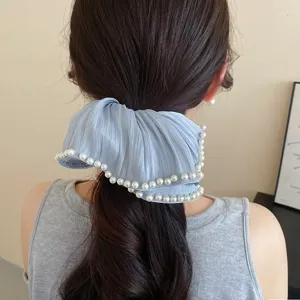 Detailweergave van een lichtblauwe geplooide stoffen haarscrunchie met prachtige parels.