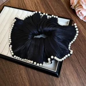 Detailopname van de elegante zwarte geplooide haarelastiek met parels in de display.
