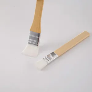 Primo piano di pennelli con manico in legno, setole bianche morbide e ghiera metallica.