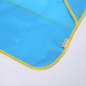 Tablier étanche pour enfants en tissu bleu gros plan de détail avec bordure jaune étiquette