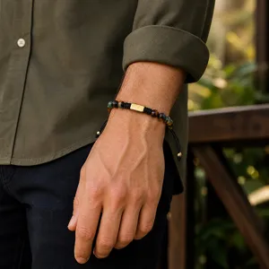 Close-up detail of men beaded gemstone bracelet with metallic center plate and adjustable cord.