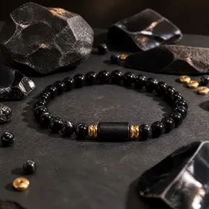 Close up detail of black obsidian and tourmaline beaded bracelet with gold accents.