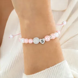 Close-up detail of the pink and white pearl bracelet featuring a sparkling crystal ball and S heart charm.