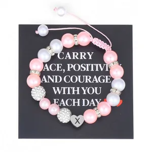 Handmade braided pink pearl bracelet with stainless steel initial heart charm detail view.
