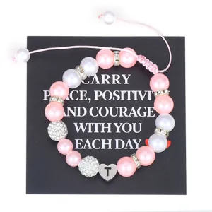 Detail view of handmade pink pearl beaded bracelet with stainless steel letter T heart charm.