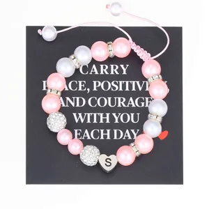 Handmade pink and white pearl bracelet detail featuring stainless steel letter S charm.