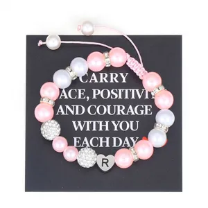 Close up detail of handmade pink pearl beaded bracelet with stainless steel letter R charm.