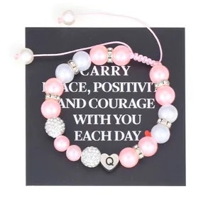 Handmade pink pearl bracelet detail view with stainless steel letter charm and rhinestones.