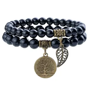 Detailed view of black natural stone double strand beaded bracelet with vintage bronze tree pendant.