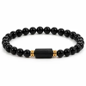 Detailed view of black obsidian beaded bracelet with elegant gold spacers and central cylinder.