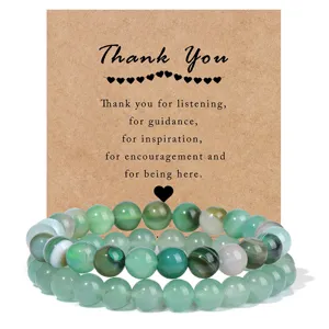 Detailed shot of green gemstone beaded bracelets with appreciation card, elegant and natural.