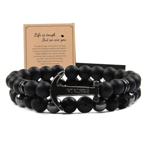 Vista detallada de pulsera de cuentas negras con dije de ancla y piedra natural.