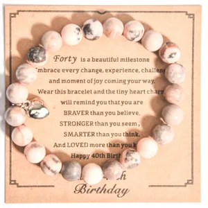 Vista detallada de pulsera de cuentas con dije de corazón en tarjeta de cumpleaños.